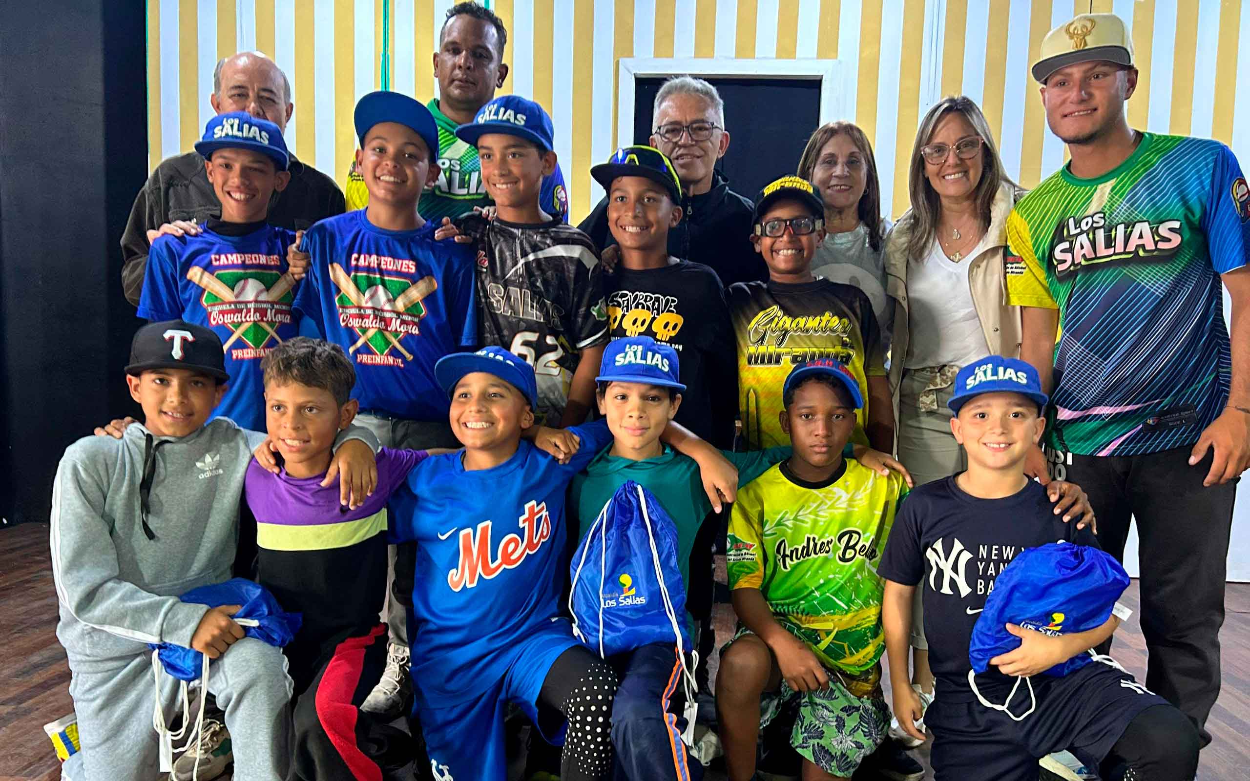 El alcalde José Fernández entregando uniformes al equipo Sub-11 de béisbol menor Los Salias, rodeado de jugadores y miembros de la comunidad.