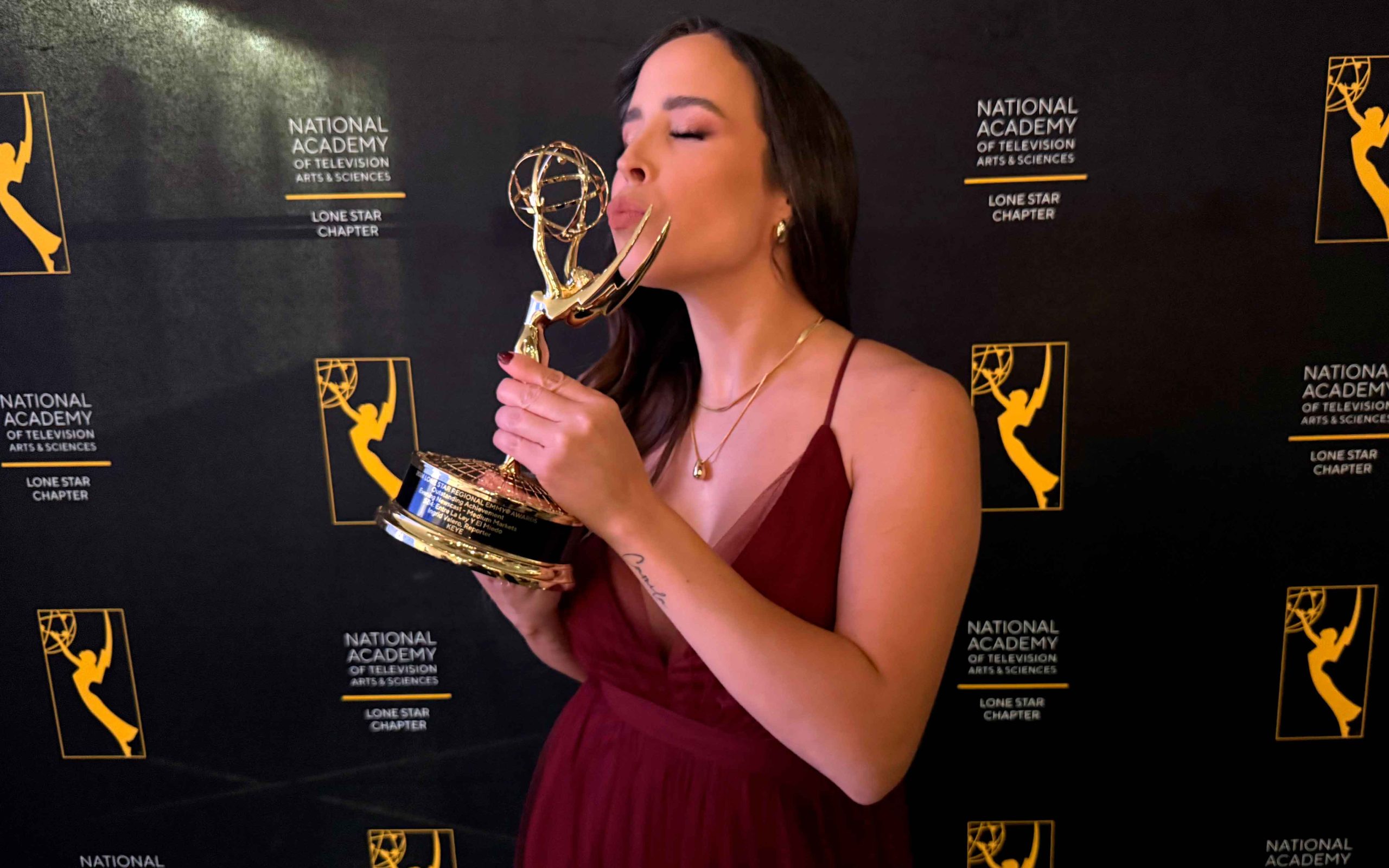 Ingrid Caribay Valero, radiante, sosteniendo su Emmy Lone Star 2024. Su sonrisa refleja el éxito y la perseverancia.