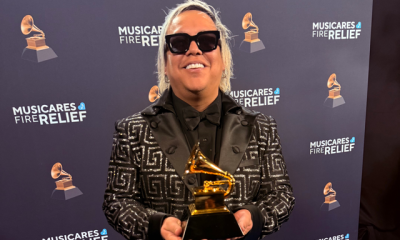 Roger Argenis, sonriente y sosteniendo su Grammy Americano, junto a Lucky Díaz y la Family Jam Band. Un momento inolvidable para este talentoso productor.