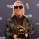 Roger Argenis, sonriente y sosteniendo su Grammy Americano, junto a Lucky Díaz y la Family Jam Band. Un momento inolvidable para este talentoso productor.